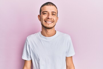 Hispanic young man wearing casual white t shirt with a happy and cool smile on face. lucky person.