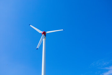 The wind turbine generates an environmentally friendly electricity in the bright blue sky.