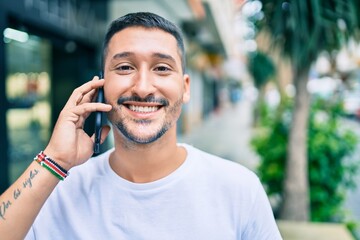Young hispanic man smiling happy talking on the smartphone at street of city.