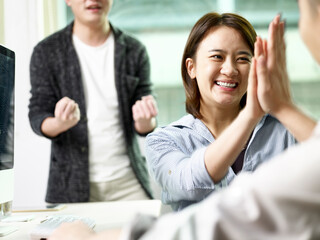 asian business people celebrating success in office