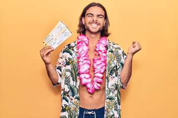 Young handsome man wearing swimwear and hawaiian lei holding boarding pass screaming proud,...