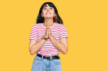 Young hispanic girl wearing casual clothes begging and praying with hands together with hope expression on face very emotional and worried. begging.