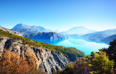 Panoramic view of the mountain lake Lac de serre-poncon in French Alps on a sunny day. Clear blue...