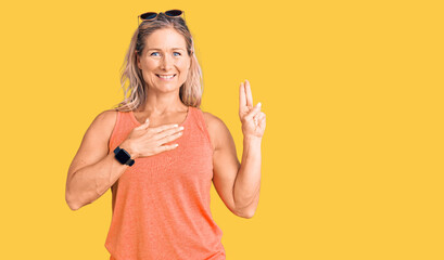 Middle age fit blonde woman wearing casual summer clothes and sunglasses smiling swearing with hand...