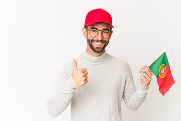 Young hispanic mixed race woman holding a portugal flag smiling and raising thumb up