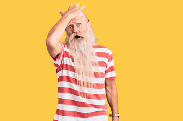 Old senior man with grey hair and long beard wearing striped tshirt surprised with hand on head for...
