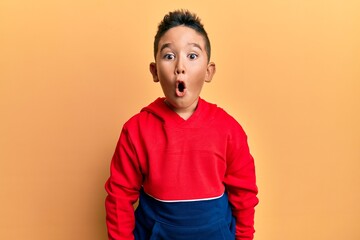 Little boy hispanic kid wearing casual sweatshirt scared and amazed with open mouth for surprise,...