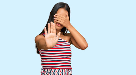 Beautiful hispanic woman wearing casual clothes covering eyes with hands and doing stop gesture with sad and fear expression. embarrassed and negative concept.