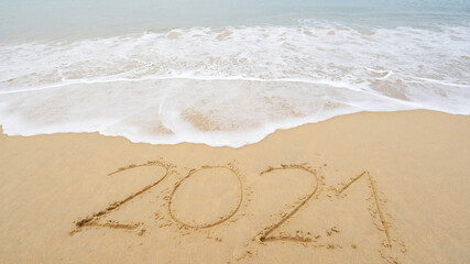 Happy New Year 2021 lettering Text on the beach with wave and white sea foam Numbers 2021 year on the seashore wave crashing on sandy shore Concept happy new year and nature new idea design background
