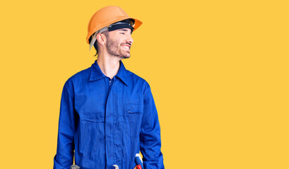 Young hispanic man wearing worker uniform looking away to side with smile on face, natural expression. laughing confident.