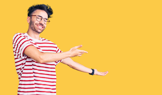 Young hispanic man wearing casual clothes inviting to enter smiling natural with open hand