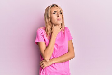Beautiful blonde woman wearing casual pink tshirt touching painful neck, sore throat for flu, clod and infection