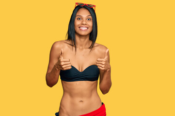 Young african american woman wearing bikini success sign doing positive gesture with hand, thumbs up smiling and happy. cheerful expression and winner gesture.