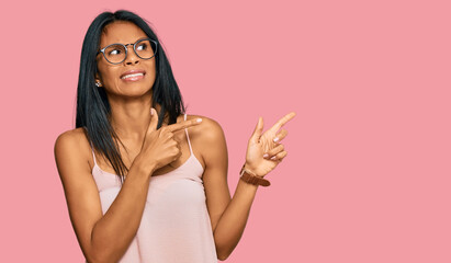 Young african american woman wearing casual clothes and glasses pointing aside worried and nervous...