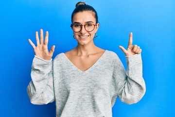 Young hispanic woman wearing casual clothes showing and pointing up with fingers number seven while smiling confident and happy.