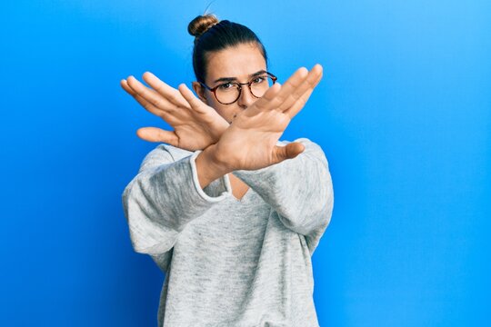 Young hispanic woman wearing casual clothes rejection expression crossing arms and palms doing negative sign, angry face