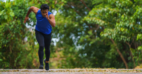 athletic sportman runner practicing sprinting run on road in park
