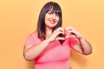 Young plus size woman wearing casual clothes smiling in love showing heart symbol and shape with hands. romantic concept.