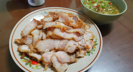 Deep fried pork belly with fish sauce, blurry seafood sauce in the background.