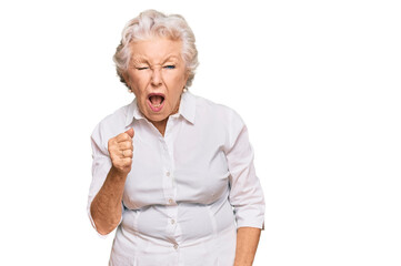 Senior grey-haired woman wearing casual clothes angry and mad raising fist frustrated and furious while shouting with anger. rage and aggressive concept.