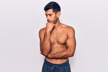 Fototapeta premium Young latin man standing shirtless looking stressed and nervous with hands on mouth biting nails. anxiety problem.