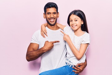 Latin father and daughter wearing casual clothes smiling happy pointing with hand and finger