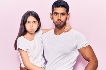 Young father and daughter wearing casual clothes puffing cheeks with funny face. mouth inflated with air, crazy expression.