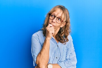Plakat Middle age blonde woman wearing casual clothes and glasses with hand on chin thinking about question, pensive expression. smiling with thoughtful face. doubt concept.
