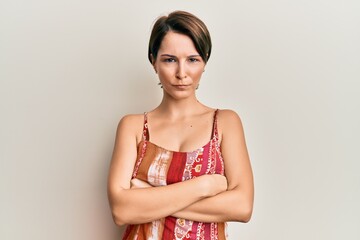 Young brunette woman with short hair wearing summer dress skeptic and nervous, disapproving...