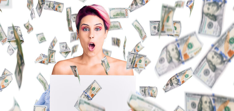 Young beautiful woman with pink hair holding cardboard banner with blank space scared and amazed with open mouth for surprise, disbelief face