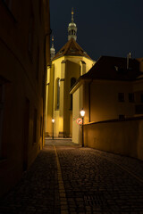 street lights on an illuminated street and pebbles on the ground in the center of the old town of prague at night in the czech republic