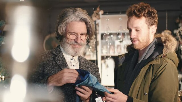 Two men choosing christmas stocking. The mature man holding blue stocking for interior decoration. Winter hoidays concept.