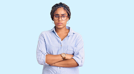 Young african american woman with braids wearing casual clothes and glasses skeptic and nervous, disapproving expression on face with crossed arms. negative person.