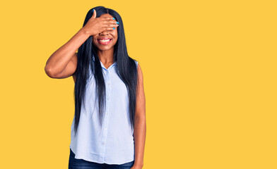 Young african american woman wearing casual clothes smiling and laughing with hand on face covering eyes for surprise. blind concept.