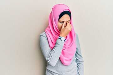 Young caucasian woman wearing traditional islamic hijab scarf tired rubbing nose and eyes feeling fatigue and headache. stress and frustration concept.