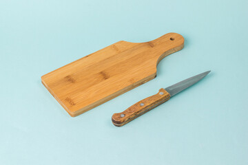 Wooden cutting Board and knife with wooden handle on blue background.