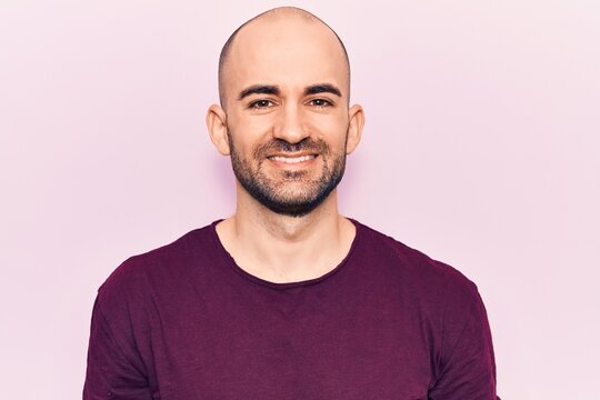 Young handsome bald man wearing casual t shirt with a happy and cool smile on face. lucky person.