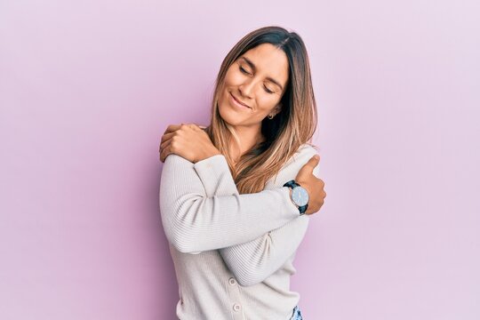 Brunette young woman wearing casual clothes hugging oneself happy and positive, smiling confident. self love and self care