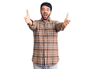 Young hispanic man wearing casual clothes looking at the camera smiling with open arms for hug. cheerful expression embracing happiness.