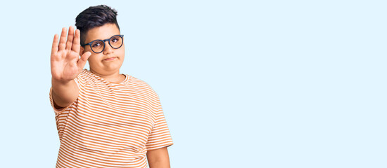 Little boy kid wearing casual clothes and glasses doing stop sing with palm of the hand. warning...
