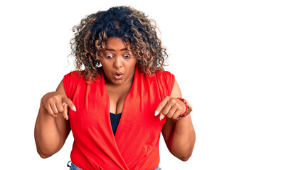 Young african american plus size woman wearing casual style with sleeveless shirt pointing down with fingers showing advertisement, surprised face and open mouth © Krakenimages.com