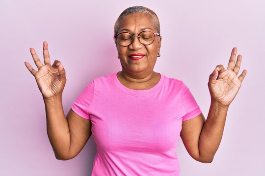 Senior african american woman wearing casual clothes and glasses relax and smiling with eyes closed doing meditation gesture with fingers. yoga concept.