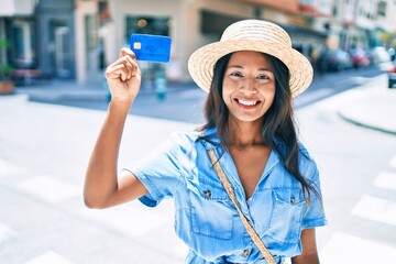 Young beautiful indian woman smiling happy holding credit card at the city.