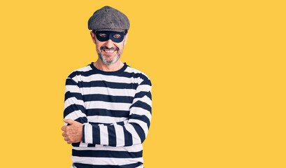 Middle age handsome man wearing burglar mask happy face smiling with crossed arms looking at the camera. positive person.