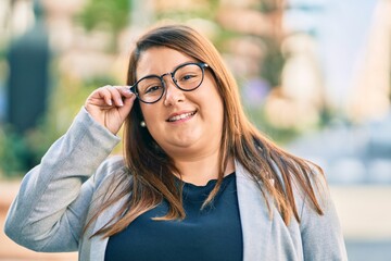 Fototapeta premium Young hispanic plus size businesswoman smiling happy standing at the city.
