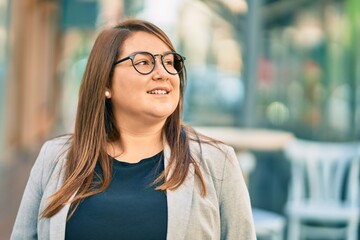 Young hispanic plus size businesswoman smiling happy standing at the city.