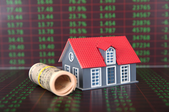 A roll of Japanese yen banknotes and a small house model on a background of financial data - Powered by Adobe