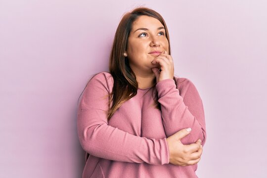 Beautiful brunette plus size woman wearing casual winter sweater thinking concentrated about doubt with finger on chin and looking up wondering