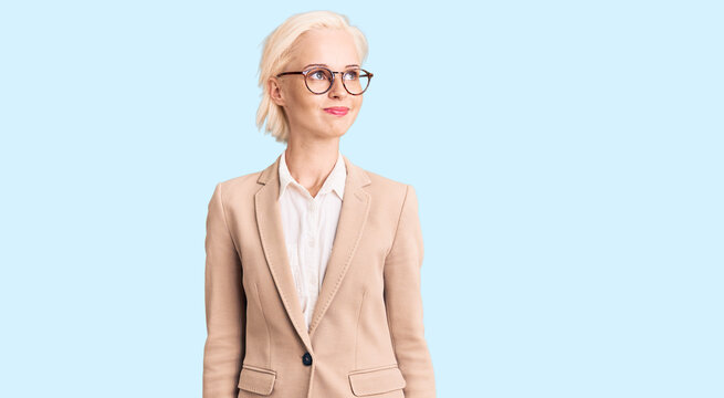 Young blonde woman wearing business clothes and glasses smiling looking to the side and staring away thinking.