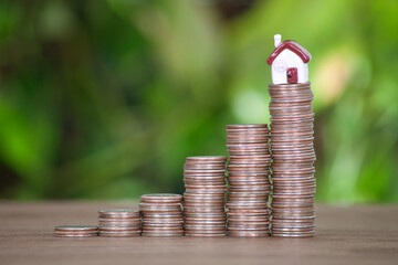 Increasing row of dollar coins and small house model